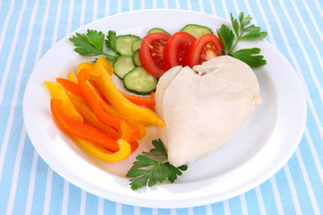 Boiled chicken breast on plate with vegetables close up