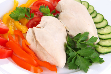 Boiled chicken breast on plate with vegetables close up