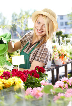 Smiling young woman watering flowers in the flowers market