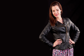 Glamorous young woman in black leather jacket on black backgroun