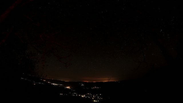 Time lapse of the night sky with clouds and stars passing by beh
