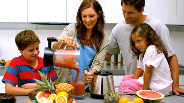 Woman with family pouring fruit cocktail from a blender