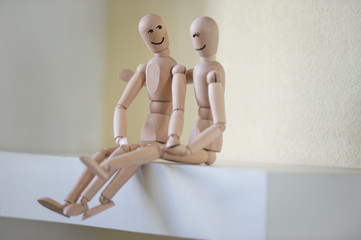 Wooden people sitting at home and hugging. People relationship c