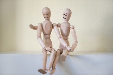 Wooden people sitting at home and hugging. People relationship c