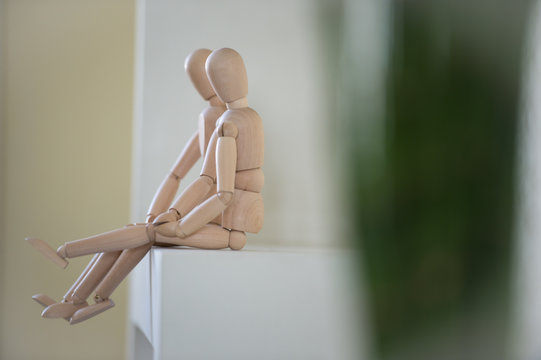 Wooden people sitting at home and hugging. People relationship c