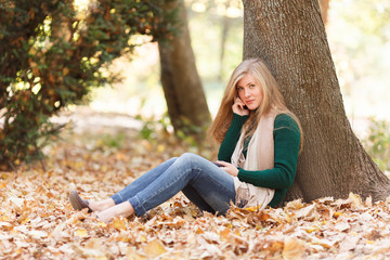 Beautiful young woman with tablet in autumn park