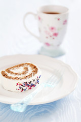 Slice of roll cake with tea and dried flower petals