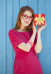 redhead girl in glasses with gift near wood background