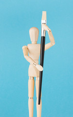 Wooden artist doll holding paint brush