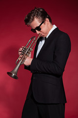 Retro fifties trumpet player wearing black suit and sunglasses.