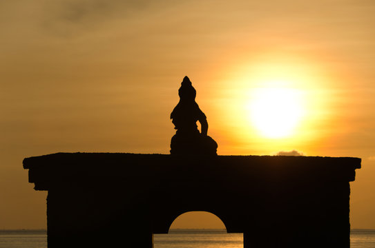 Silhouette of sitting Buddha against rising sun