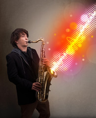 Fototapeta na wymiar Young man playing on saxophone with colorful sound waves