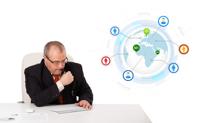 businessman sitting at desk and typing on keyboard with globe an