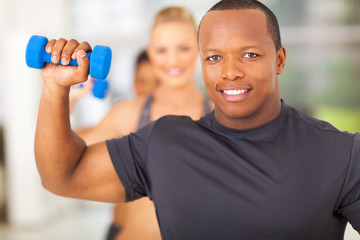 african man exercising in gym with dumbbell
