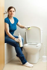 woman cleaning toilet bowl with sponge
