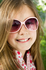 Happy little girl with glasses posing in the grass
