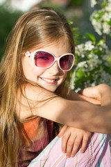 Happy little girl with glasses posing in the grass