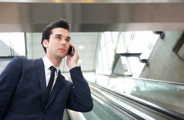 Traveling businessman talking on the phone on escalator