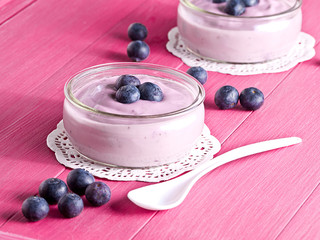 Joghurt mit Heidelbeeren auf einem Holztablett.