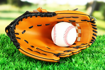 Baseball glove and ball on grass in park
