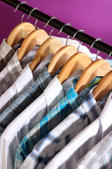 Men's shirts on hangers on purple background