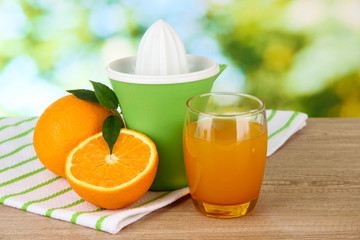 Citrus press, glass of juice and ripe oranges
