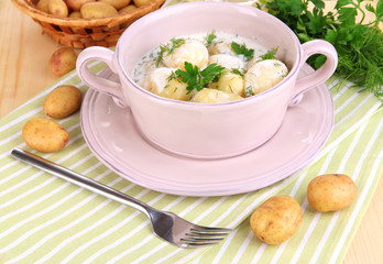 Tender young potatoes with sour cream and herbs in pan