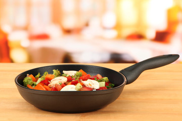 Vegetable ragout in pan,  on wooden table on bright background