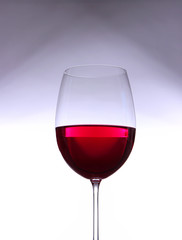 Glass with red wine on gray-white gradient background
