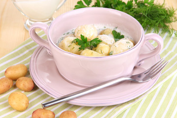 Tender young potatoes with sour cream and herbs in pan