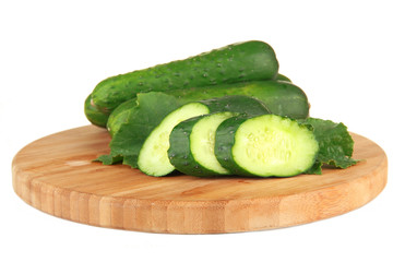 Tasty green cucumbers on wooden cutting board, isolated on