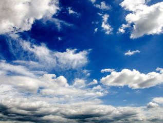 Sommerlicher Himmel mit weißen Wolken und Gewitter-Wolken