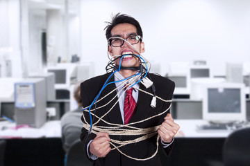 Crazy businessman tied in cable and rope at office
