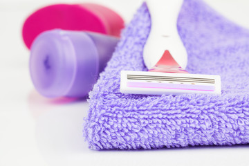 Closeup of pink shaving blade on towel with moisturizer
