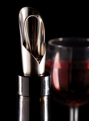 bottle with a special nozzle for wine pouring and a wine glass..