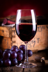 Glas Rotwein vor antiker Weinkiste