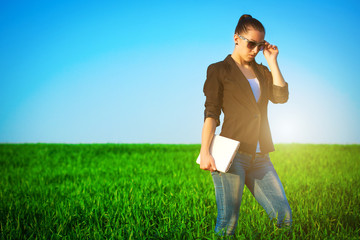 sexy businesswoman in a green field with a laptop. idea