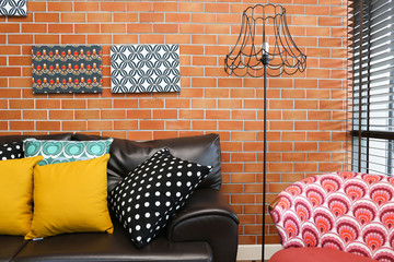 Colorful pillows on a sofa with brick wall in background