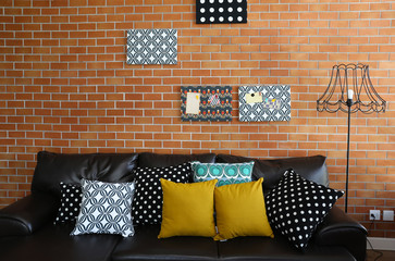 Colorful pillows on a sofa with brick wall in background