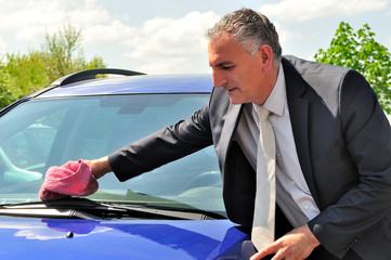 Man wearing suit cleaning a car.