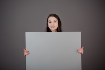 A woman holds a blank gray surface.