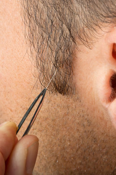 Mann entfernt erstes graues Haar mit Pinzette