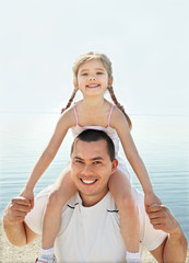 Little girl with her father having fun on beach vacation