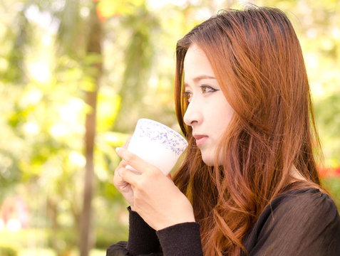 Beautiful asian woman holding coffee cup in morning time