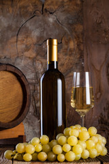 Naklejka premium White wine, grapes, old bottle and a barrel.