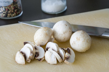 Champignons geschnitten auf einem weißen Brett mit Messer