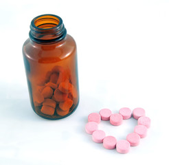 Heart shape pills with a bottle on white background