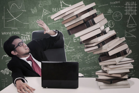 Stress businessman with falling books at class