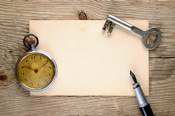 Vintage pocket watch, fountain pen, key and old postcard