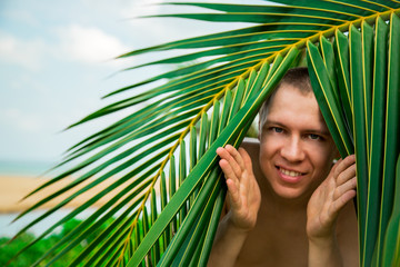 The man poses on a background of palm trees